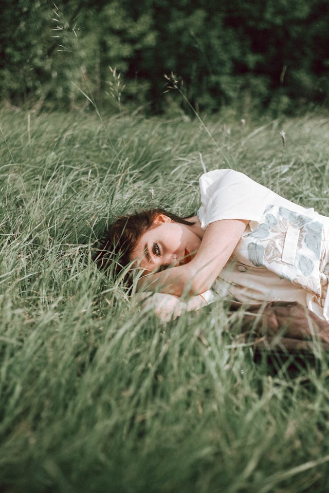 woman peeking over grass blades
