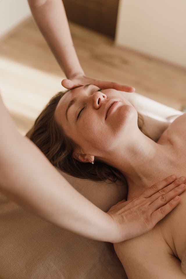 A person receiving a massage, with a focus on the hands applying pressure to the neck and shoulders.