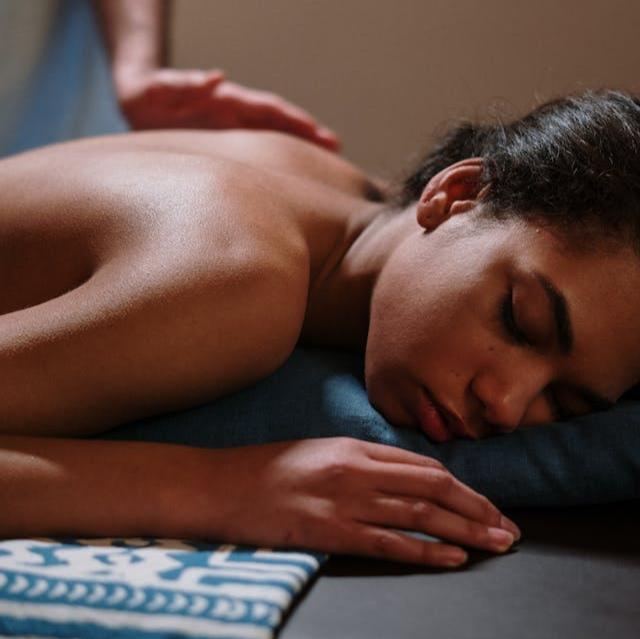 A person lying down on a massage table, receiving a lymphatic massage.